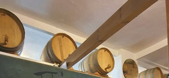 Σειρά από ξύλινα βαρέλια κρασιού στο ράφι, κάτω από το ξύλινο πατάρι.