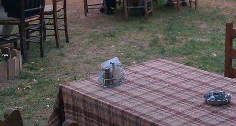 Παραδοσιακές ξύλινες καρέκλες με ψάθινο κάθισμα, γύρω από στρωμένο τραπέζι.